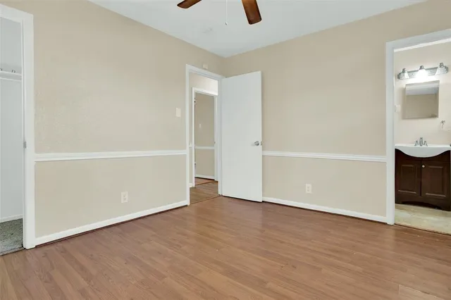 a view of an empty room with wooden floor and a ceiling fan