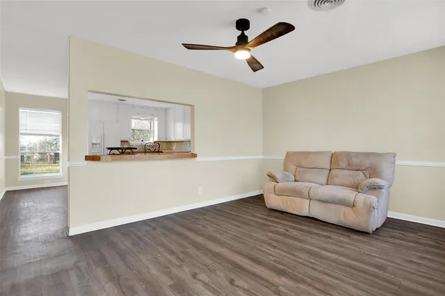 a living room with stainless steel appliances kitchen island granite countertop wooden floor a couch and a window