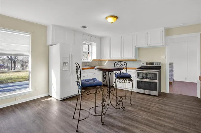 a kitchen with stainless steel appliances a stove a table and chairs in it