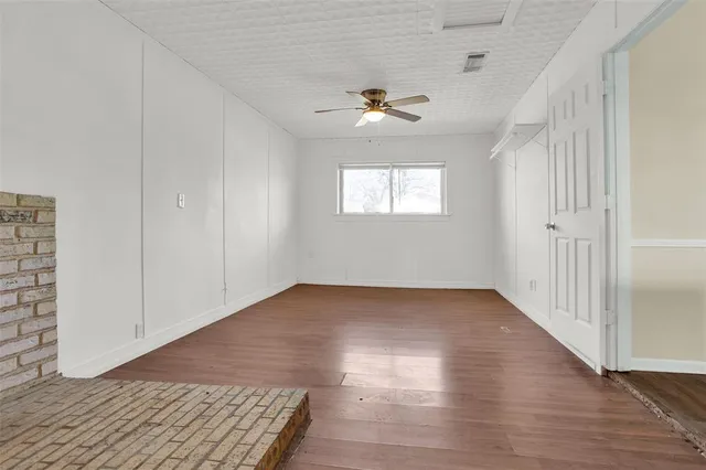 an empty room with wooden floor chandelier and windows
