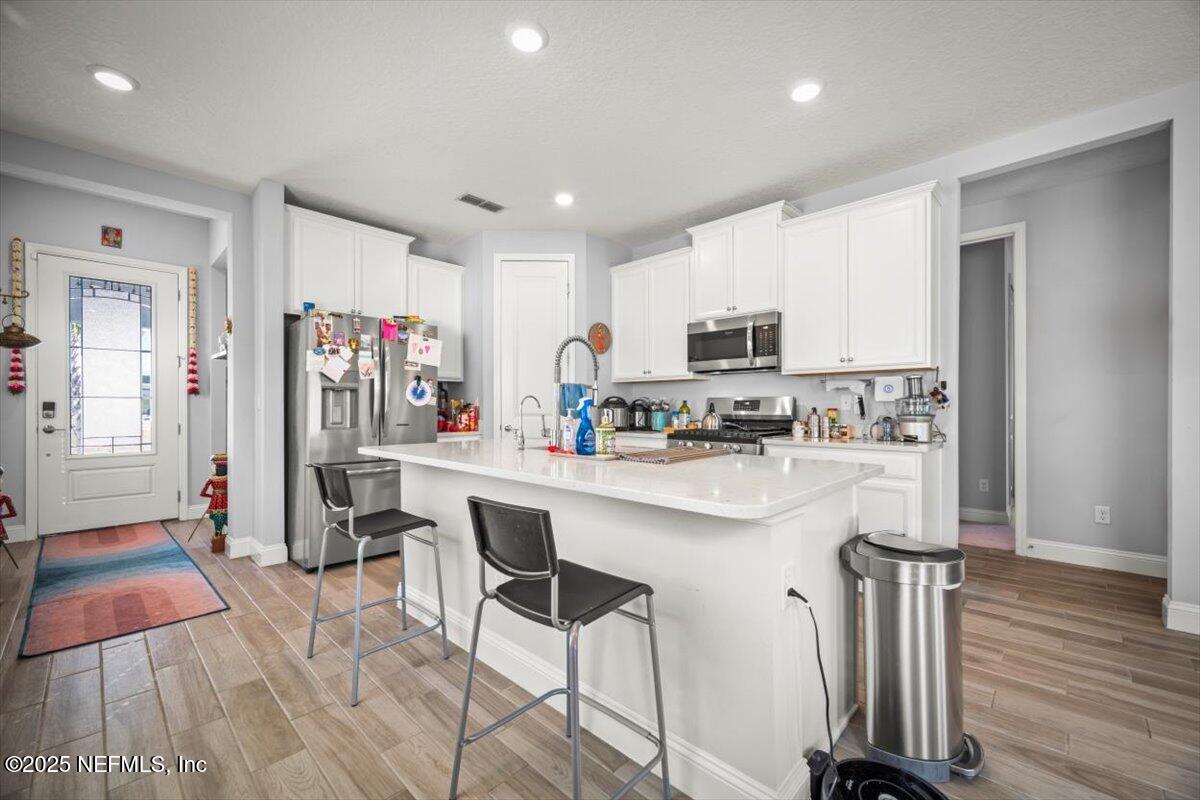 141 Killarney Avenue St. Johns, FL 32259 - Photo 3 of 33 a kitchen with stainless steel appliances granite countertop a refrigerator oven a sink dishwasher and white cabinets with wooden floor