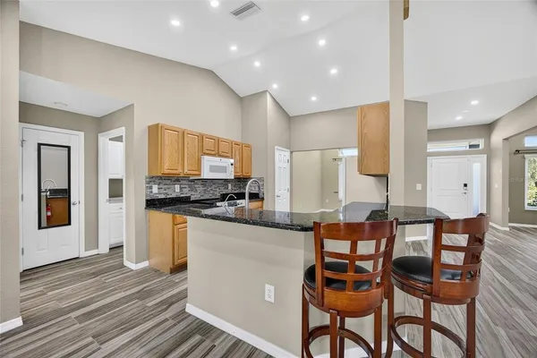 a kitchen with stainless steel appliances kitchen island granite countertop a table and chairs in it