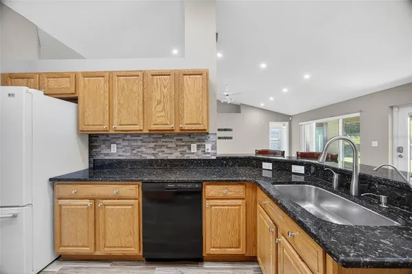a kitchen with granite countertop a sink a counter space and stainless steel appliances