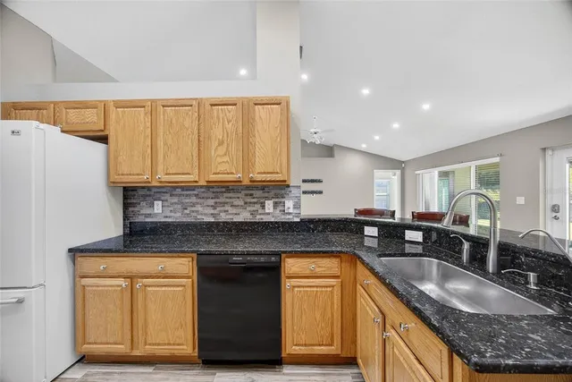 a kitchen with granite countertop a sink a counter space and stainless steel appliances