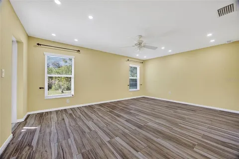 a view of an empty room with wooden floor and a window