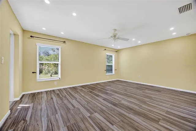 a view of an empty room with wooden floor and a window