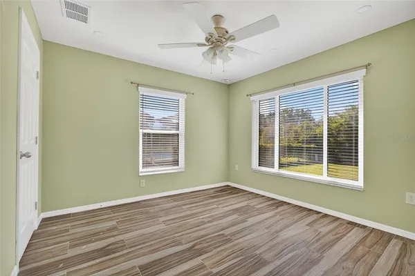 a view of an empty room with a window and wooden floor