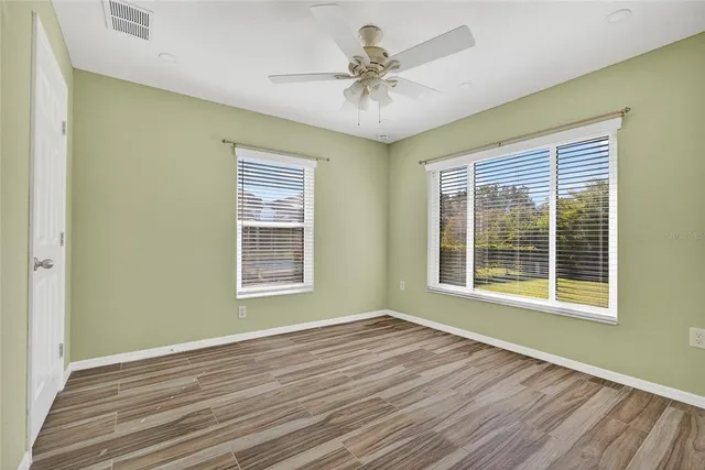 a view of an empty room with a window and wooden floor