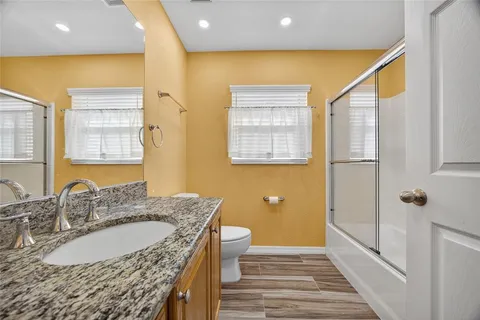 a bathroom with a granite countertop double vanity sink a mirror and a shower