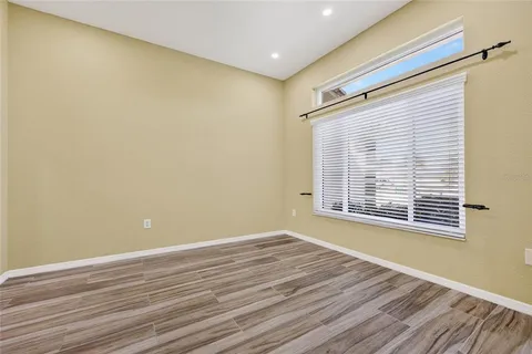 a view of an empty room with wooden floor and a window