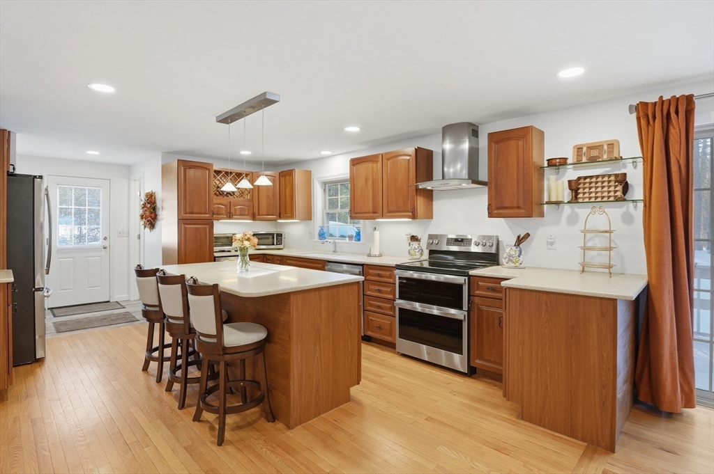 17 Longley Road Shirley, MA 01464 - Photo 6 of 33 a kitchen with stainless steel appliances granite countertop a stove top oven a refrigerator a sink and a dining table with wooden floor