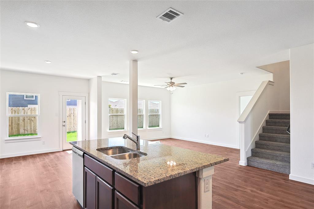 213 Patton Lane Venus, TX 76084 - Photo 11 of 30 Kitchen with dark wood finish cabinetry, light stone counters, dark wood-type flooring, an island with sink, and dishwasher