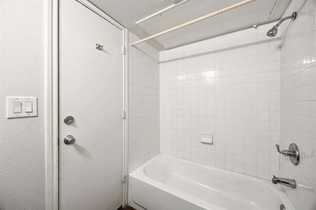 9837 Walnut Street, Unit S203 Dallas, TX 75243 - Photo 22 of 26 The bathroom features a white bathtub with a showerhead and faucet, surrounded by white tiled walls