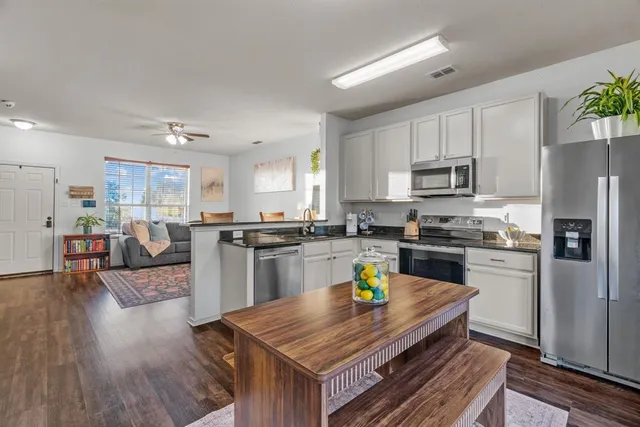 a kitchen with a refrigerator a stove top oven a sink dishwasher and white cabinets with wooden floor