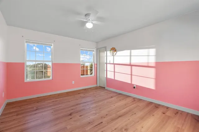 an empty room with wooden floor and windows