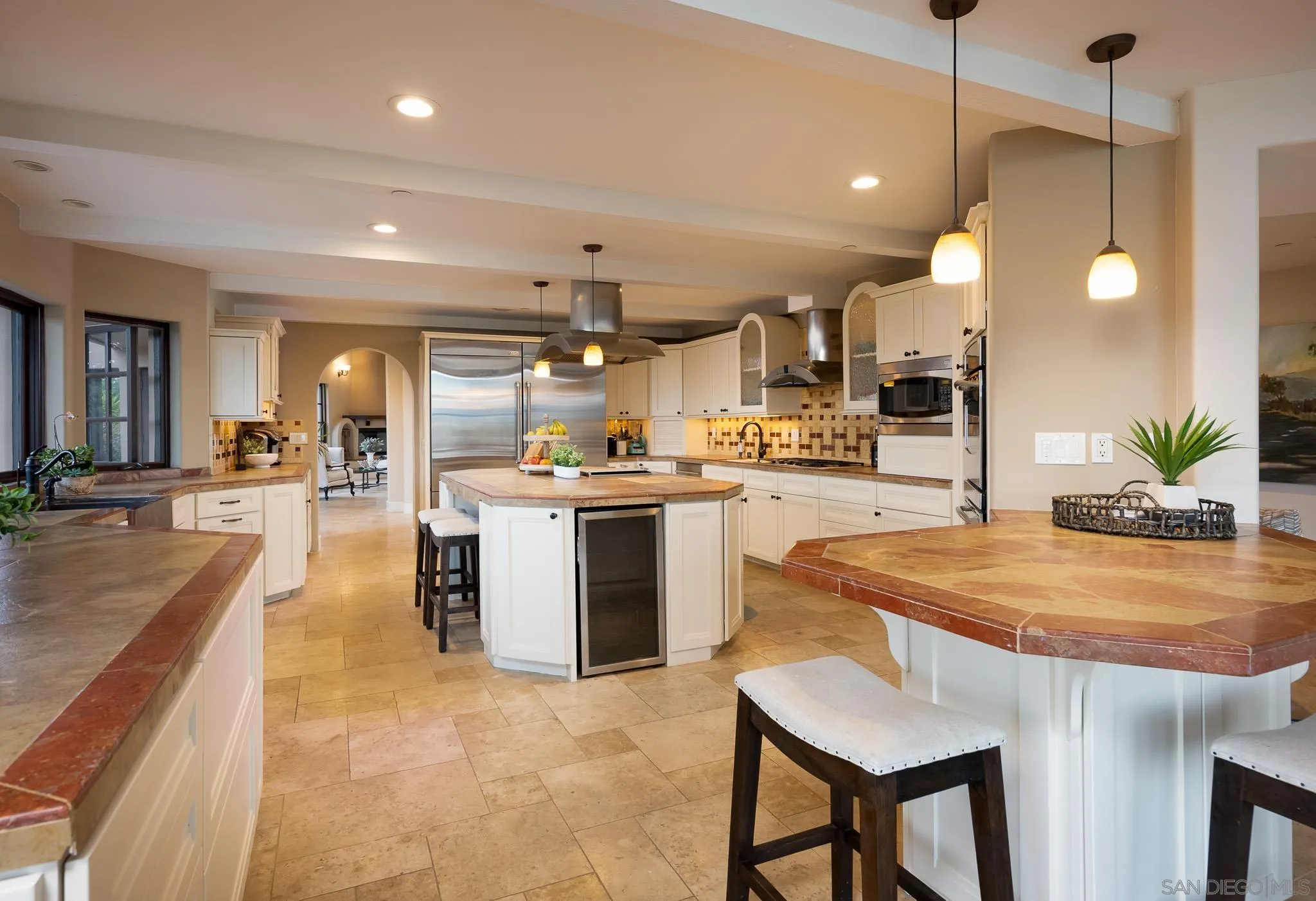 16738 Zumaque Street Rancho Santa Fe, CA 92067 - Photo 19 of 61 a kitchen with kitchen island a stove a sink a refrigerator and a fireplace