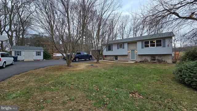 a front view of a house with a yard covered with trees