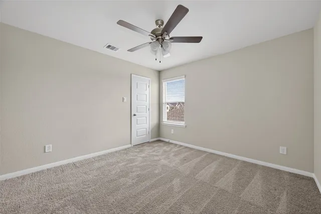 an empty room with a ceiling fan and window