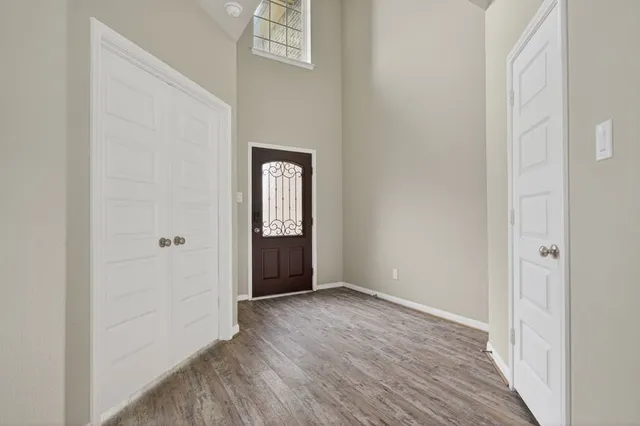 a view of an empty room with closet and wooden floor