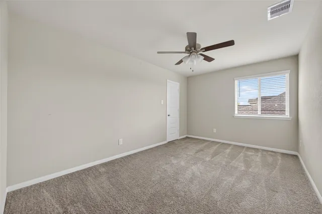 an empty room with windows and ceiling fan