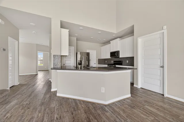 a view of kitchen with stainless steel appliances granite countertop a stove top oven a refrigerator a sink and dishwasher with wooden floor