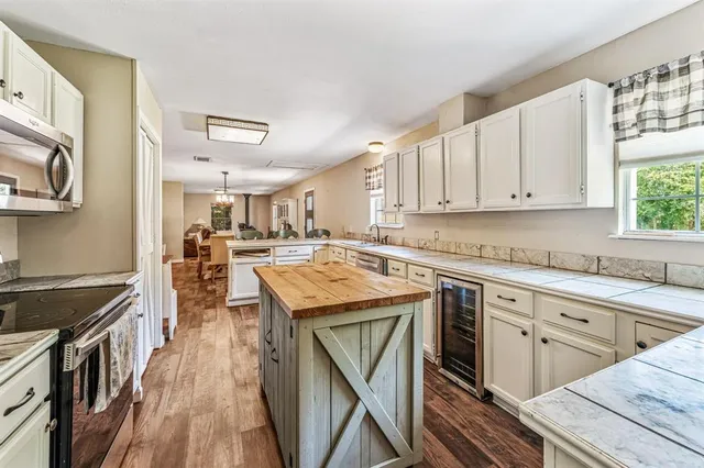 a kitchen with stainless steel appliances granite countertop a stove top oven a sink dishwasher and white cabinets with wooden floor