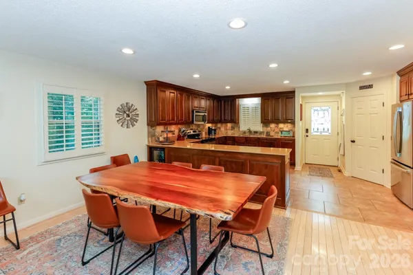 a kitchen with stainless steel appliances granite countertop a table chairs sink refrigerator and cabinets