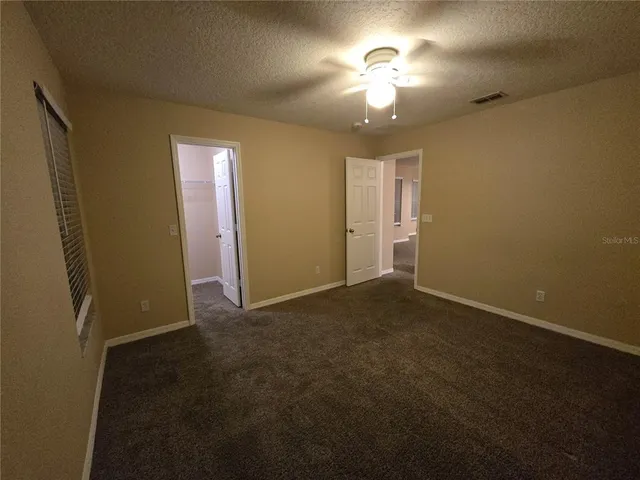 an empty room with windows and fan