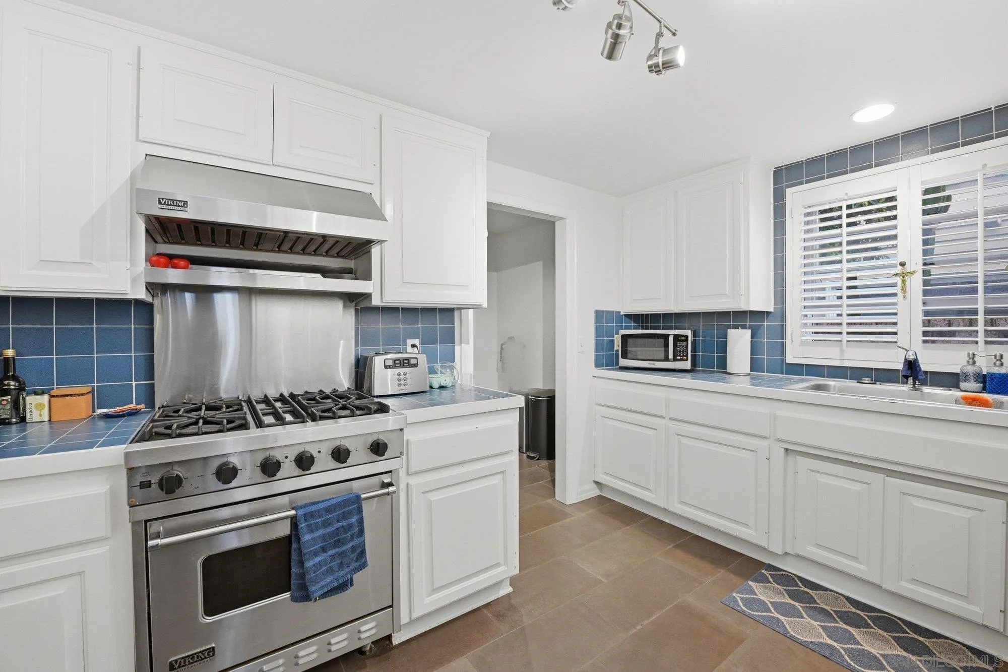 711 Kline Street, Unit A La Jolla, CA 92037 - Photo 6 of 20 a kitchen with stainless steel appliances white cabinets and a stove top oven