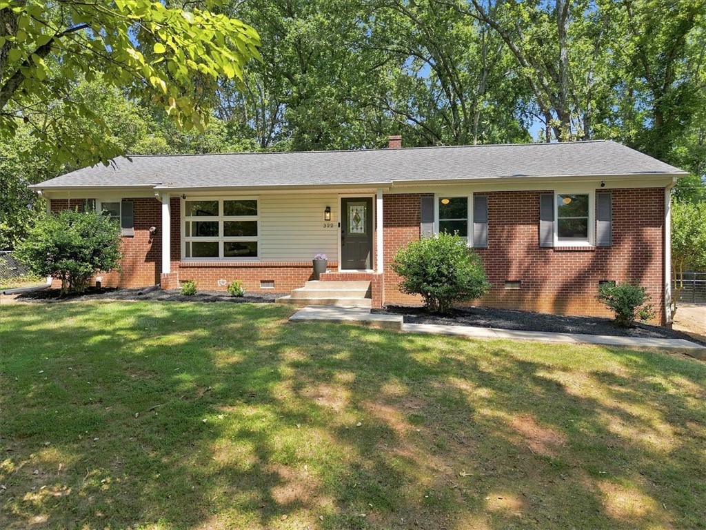 Mature trees frame a classic single-story brick facade complete with a neat lawn.