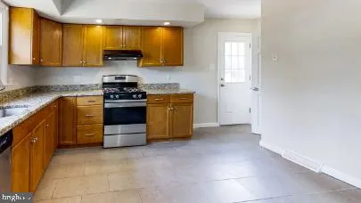 a kitchen with stainless steel appliances granite countertop a stove a sink and a refrigerator