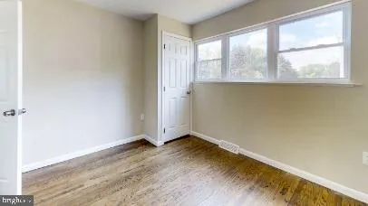 an empty room with wooden floor and windows