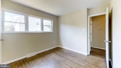 an empty room with wooden floor and a window