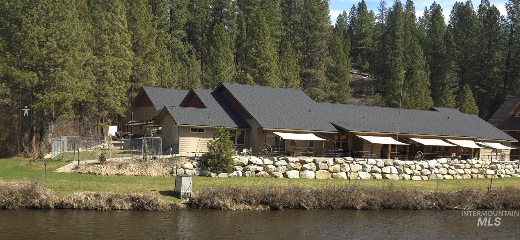 Rear view of house featuring a water view, a patio area, and a forest view