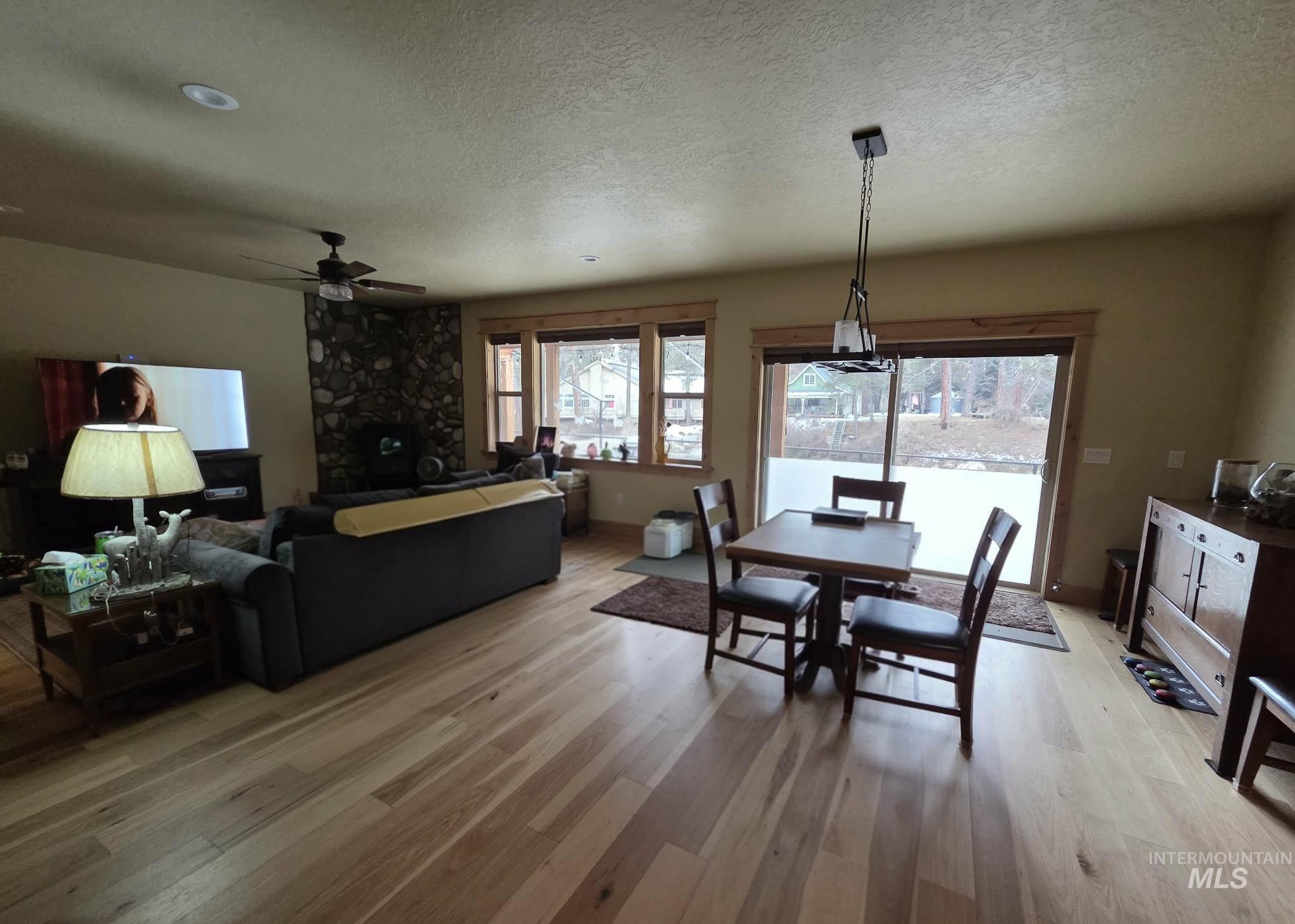 36 Kevins Way Garden Valley, ID 83622 - Photo 16 of 50 Dining room with light wood-type flooring, a textured ceiling, a ceiling fan, and a fireplace