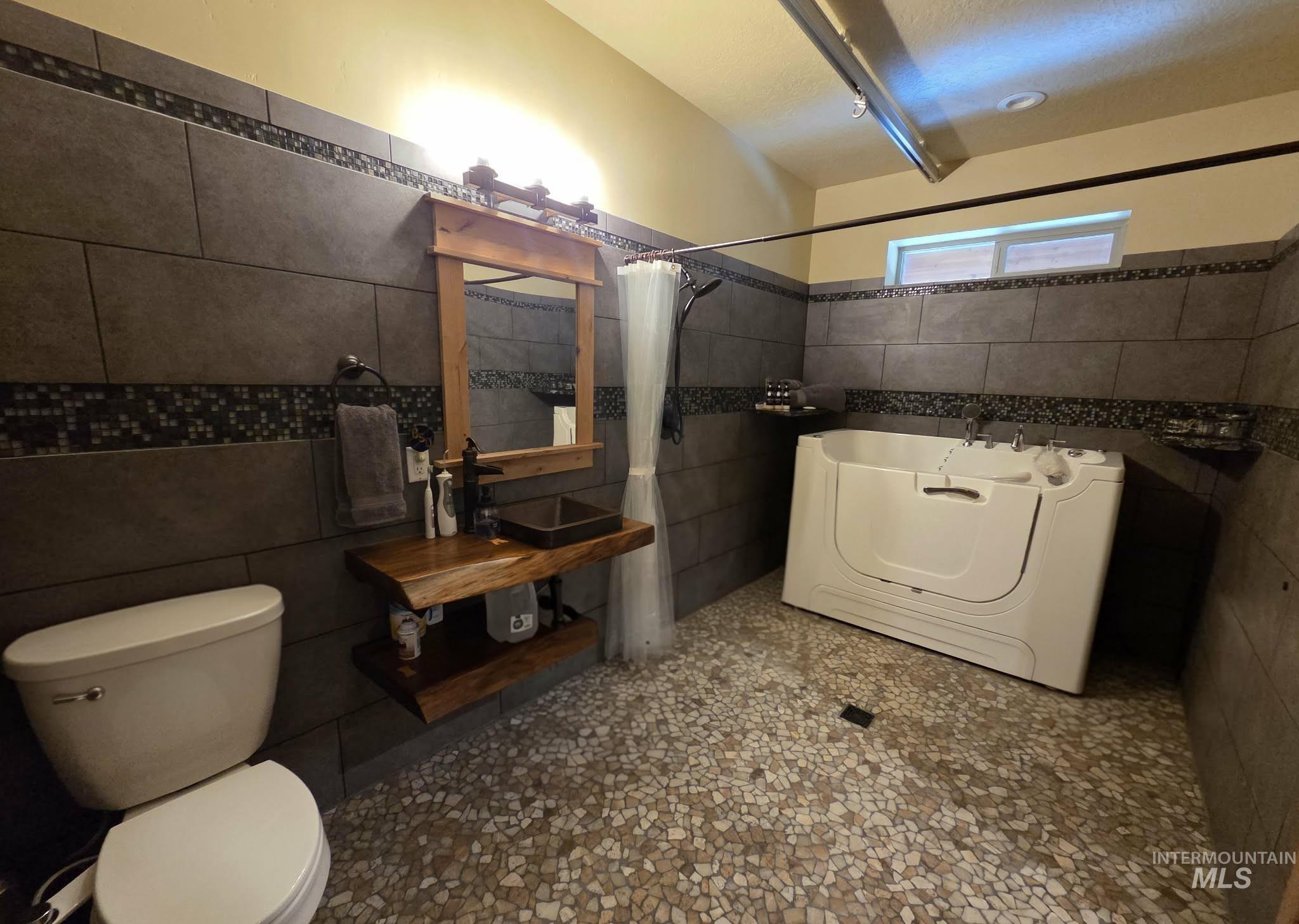 36 Kevins Way Garden Valley, ID 83622 - Photo 21 of 50 Full bath with tile walls, washer / dryer, a tub, and a shower with shower curtain