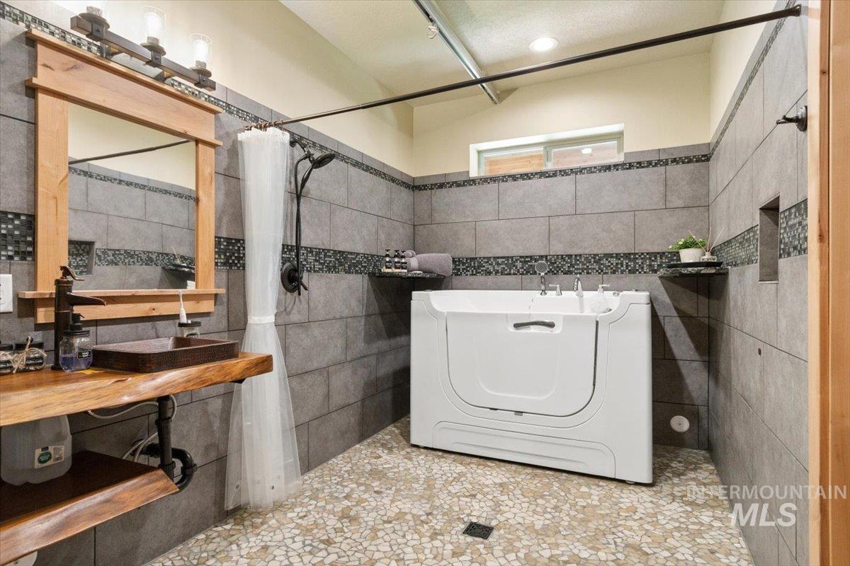 36 Kevins Way Garden Valley, ID 83622 - Photo 25 of 50 Full bath with tile walls, washer / dryer, a tub, and a shower with shower curtain