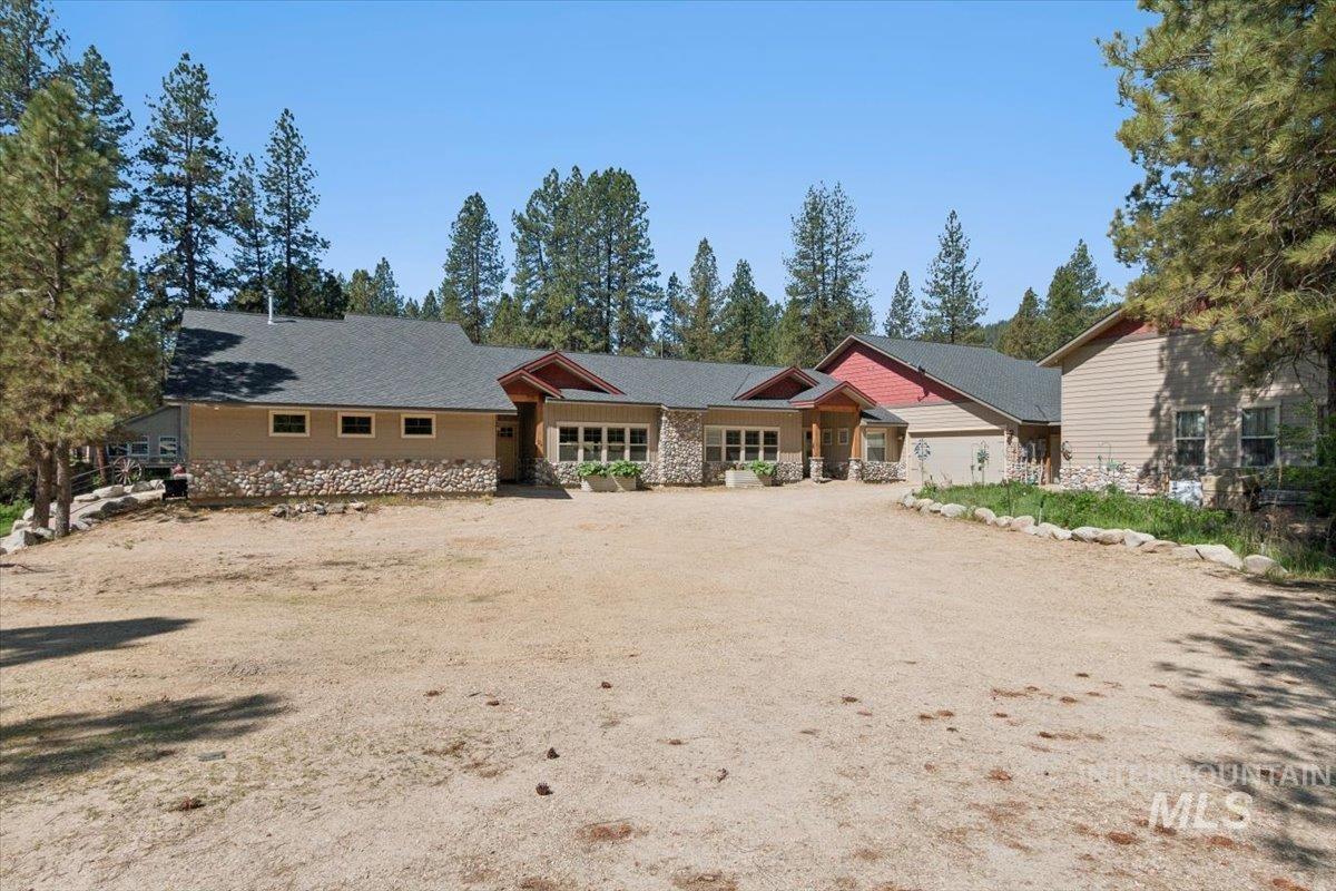 36 Kevins Way Garden Valley, ID 83622 - Photo 5 of 50 View of front of home featuring stone siding, a shingled roof, a garage, dirt driveway, and a porch