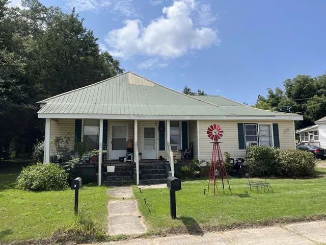 a front view of a house with a yard garden and patio