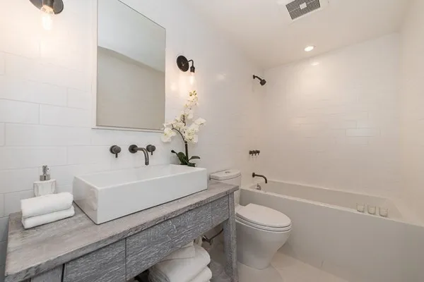 a bathroom with a white toilet a sink and a mirror