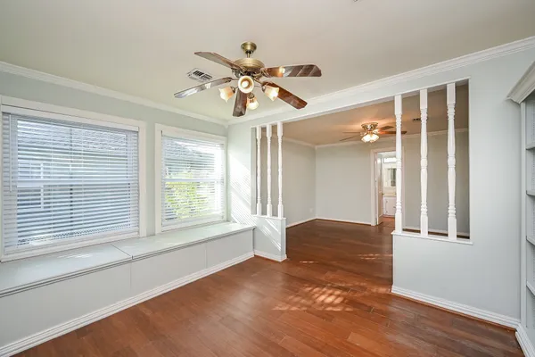 a view of an empty room with window and wooden floor