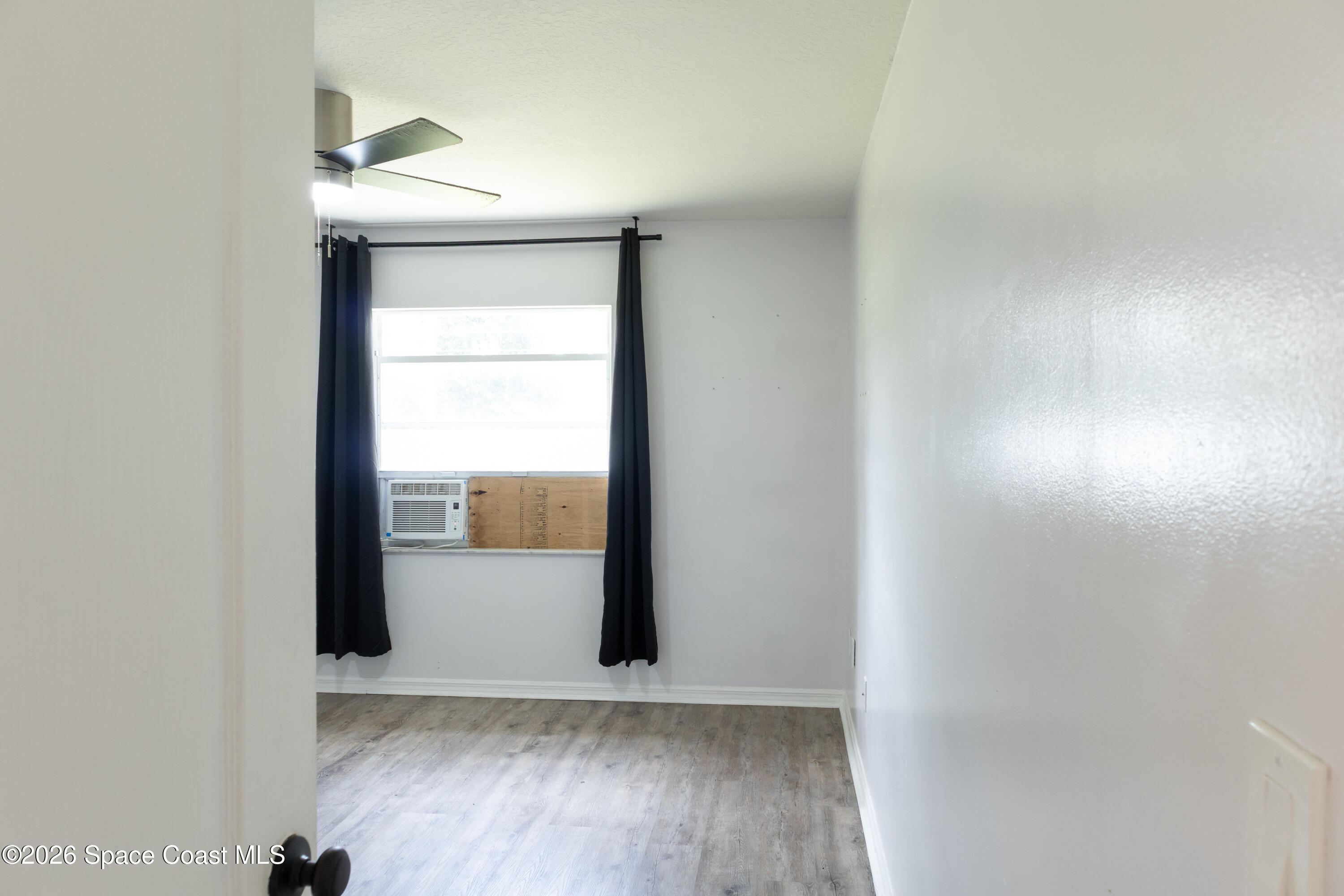 1572 Holbrook Road Northwest Palm Bay, FL 32907 - Photo 19 of 38 an empty room with wooden floor and windows