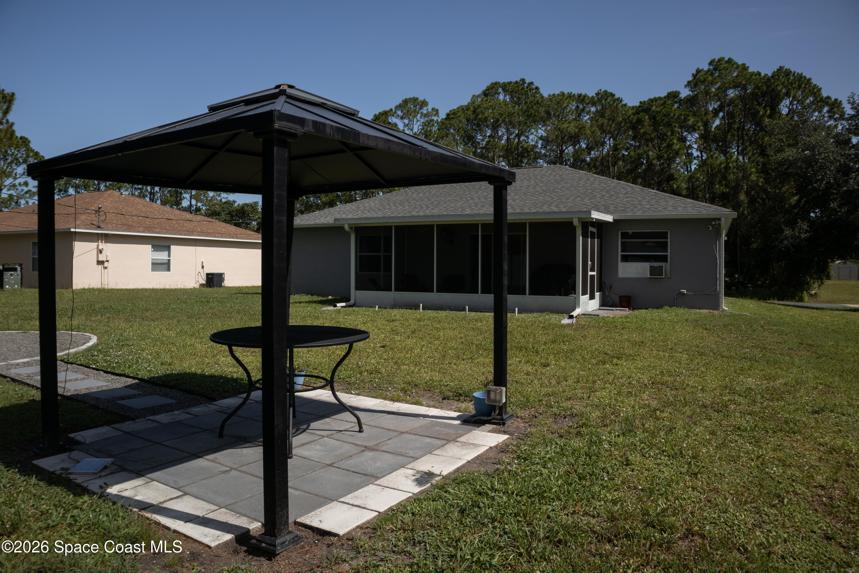 1572 Holbrook Road Northwest Palm Bay, FL 32907 - Photo 5 of 38 a view of a chair and table in backyard of the house