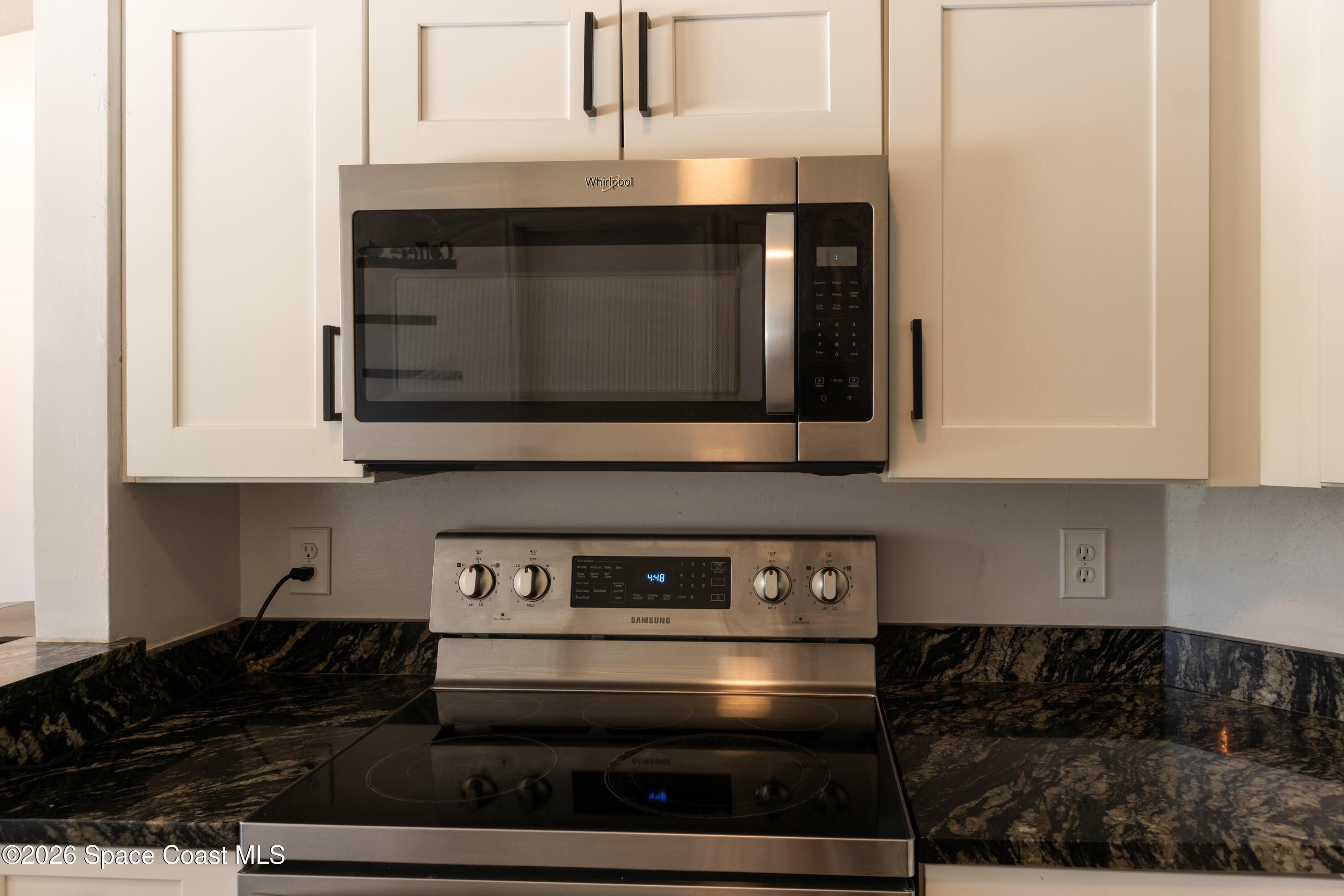 1572 Holbrook Road Northwest Palm Bay, FL 32907 - Photo 10 of 38 a kitchen with granite countertop white cabinets and black stove