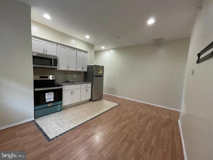 4726 Chestnut Street, Unit 8 Philadelphia, PA 19139 - Photo 2 of 9 a kitchen with stainless steel appliances granite countertop a refrigerator a stove top oven a sink and dishwasher with wooden floor