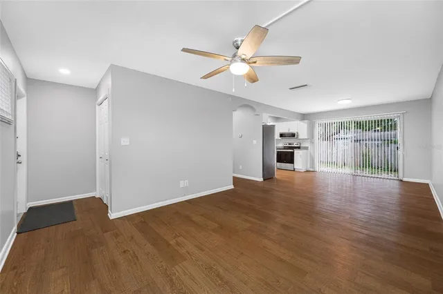 a view of empty room with wooden floor and fan