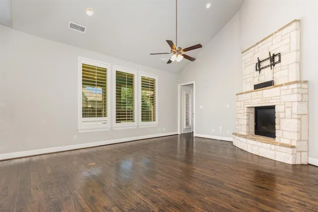 a view of an empty room with wooden floor fireplace and a window