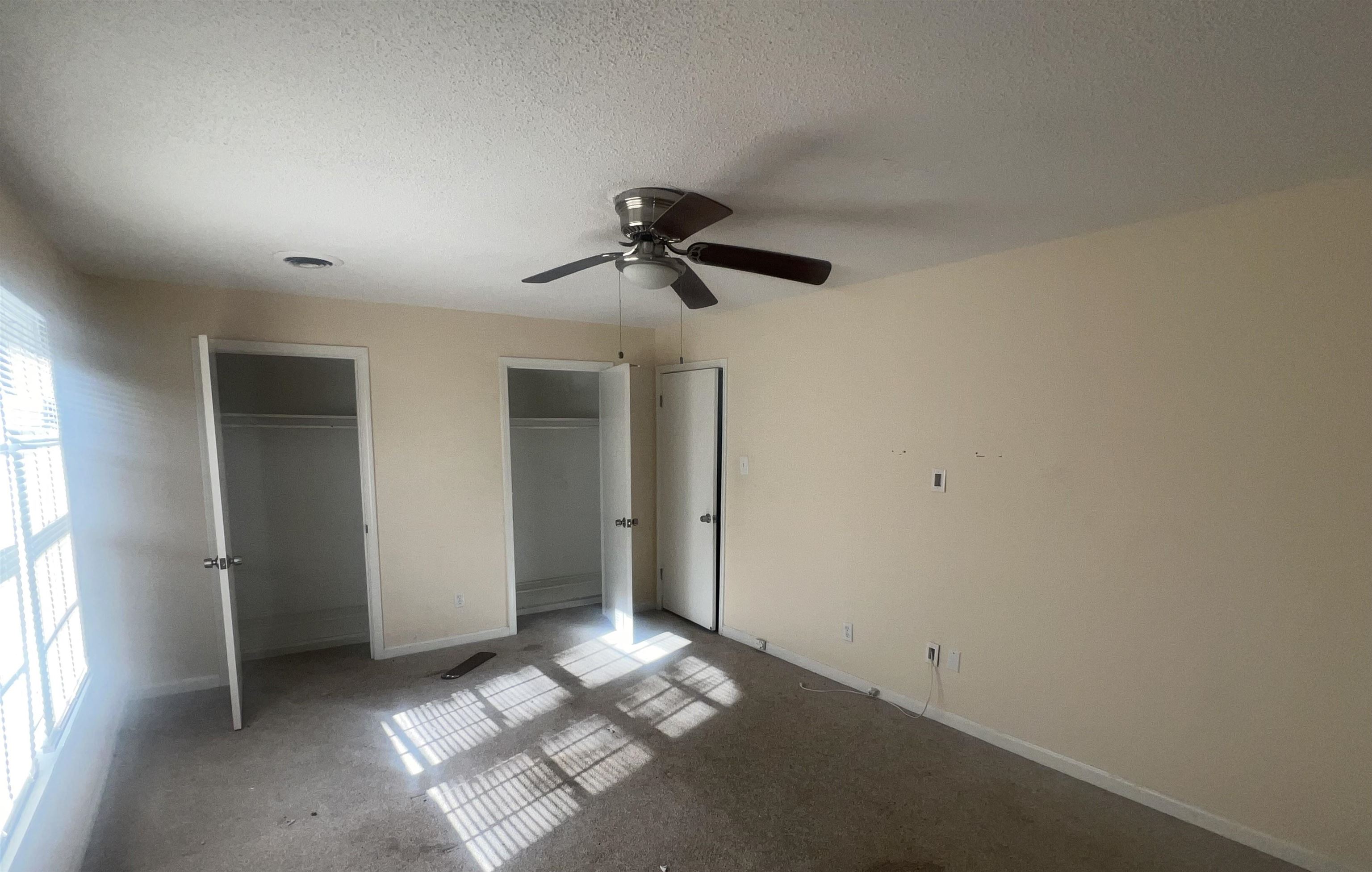 4295 Hudgins Road Memphis, TN 38116 - Photo 12 of 16 Room featuring two closet spaces with white doors, a ceiling fan with integrated lighting, and a large window with white blinds