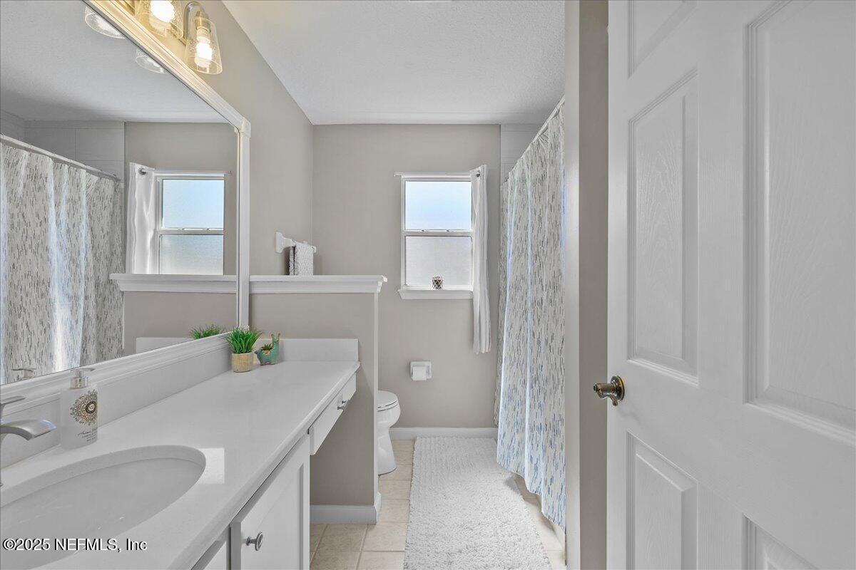 1940 Bluebonnet Way Fleming Island, FL 32003 - Photo 19 of 44 a bathroom with a granite countertop sink a toilet and shower