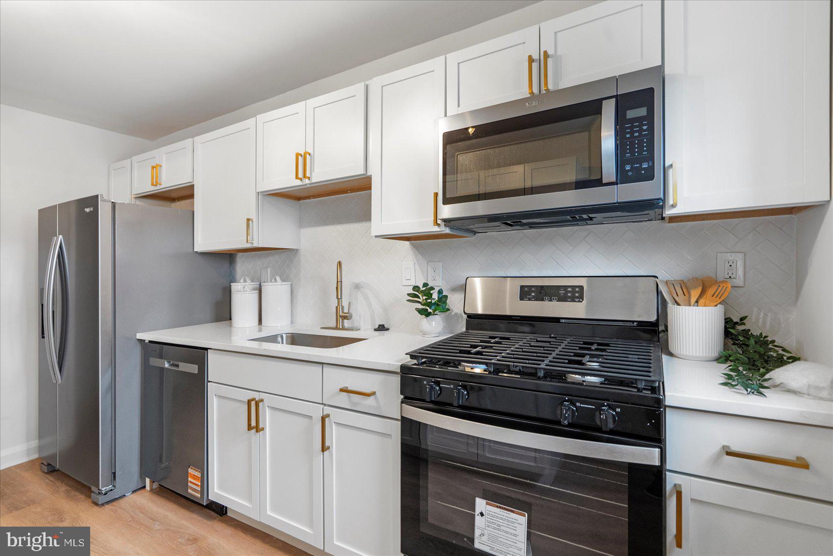 2210 Walshire Avenue Baltimore, MD 21214 - Photo 16 of 42 a kitchen with stainless steel appliances granite countertop white cabinets a stove a microwave and a refrigerator